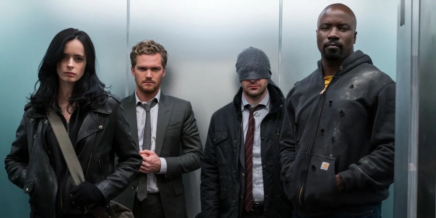 Krysten Ritter as Jessica Jones, Finn Jones as Danny Rand, Charlie Cox as Matt Murdock, and Mike Colter as Luke Cage standing in an elevator in The Defenders | Agents of Fandom