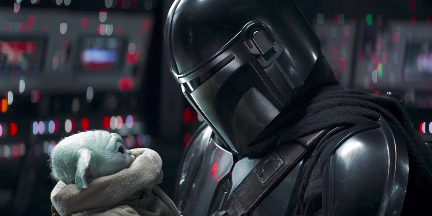 The Mandalorian holding Grogu close to his helmet in the Mandalorian Season 2 finale | Agents of Fandom