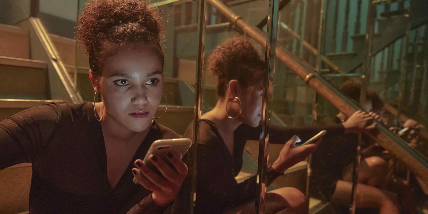 Emma McDonald siting on steps beside a mirror holding her phone in 7 Keys | Agents of Fandom