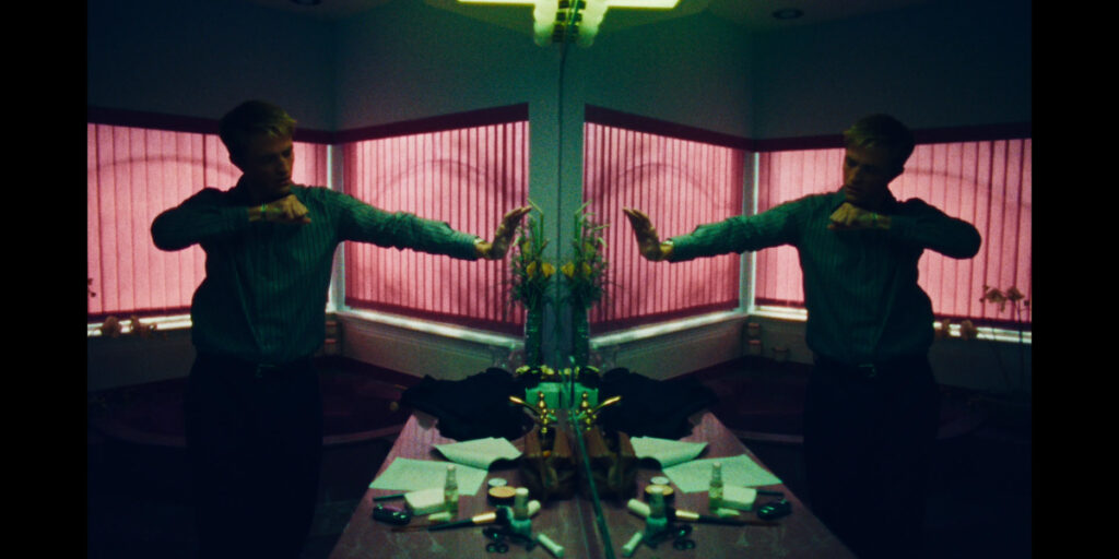 Robert Pattinson making a fist and looking at himself in the mirror in Primetime | Agents of Fandom